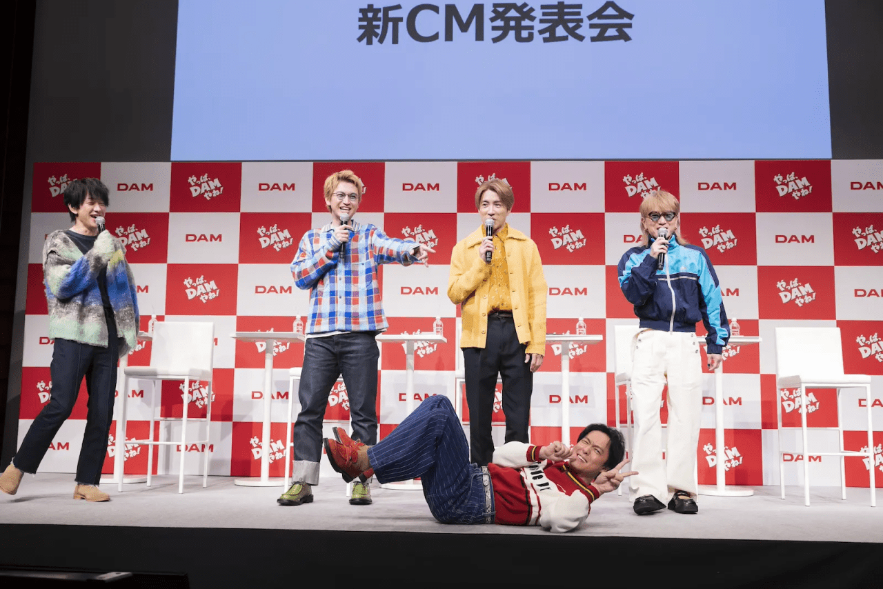 Members of SUPER EIGHT performing at a new CM announcement event for DAM, engaging with the audience and showcasing playful energy.