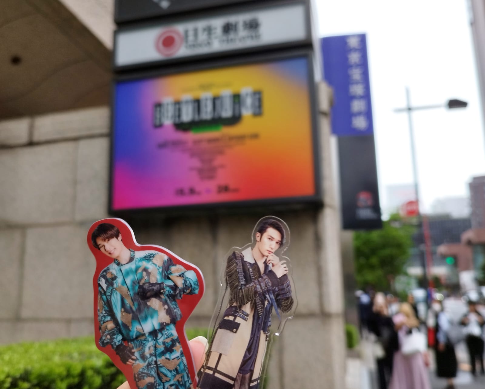 A close-up of two figurines representing characters from the musical 'Beetlejuice' in front of a theater sign displaying information about the performance.
