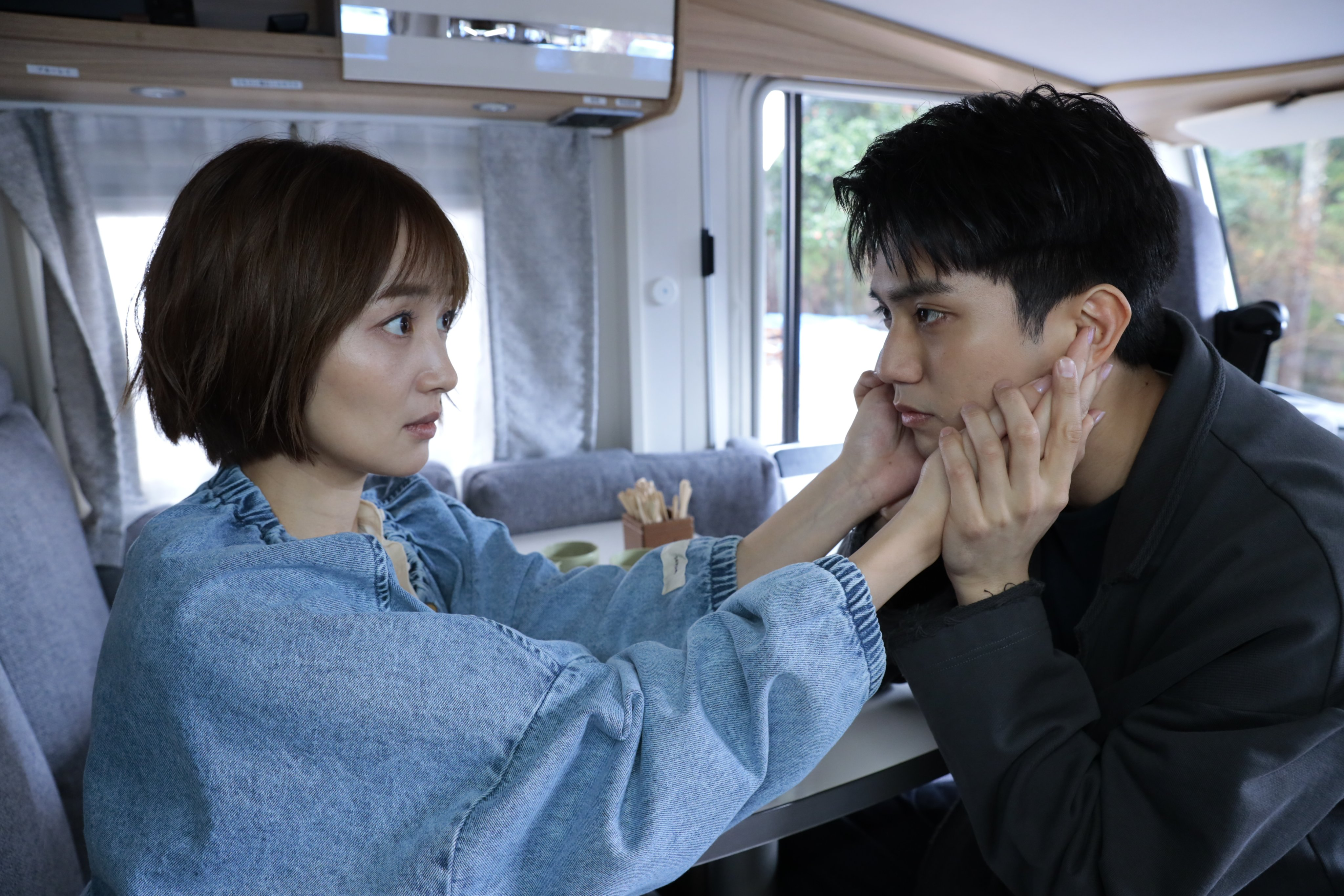 A scene from 'Musashino Rondo' featuring a close-up of a woman holding a man's face as they share a moment of emotional intensity in a cozy interior setting.