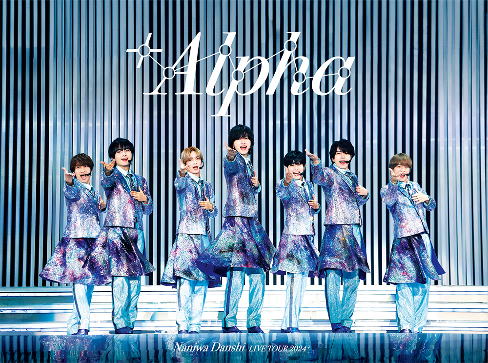 A group of seven male performers from Naniwa Danshi in sparkly outfits, striking dynamic poses on stage during their concert titled '+Alpha.' The background features vertical stripes, enhancing the stage's vibrant ambiance.