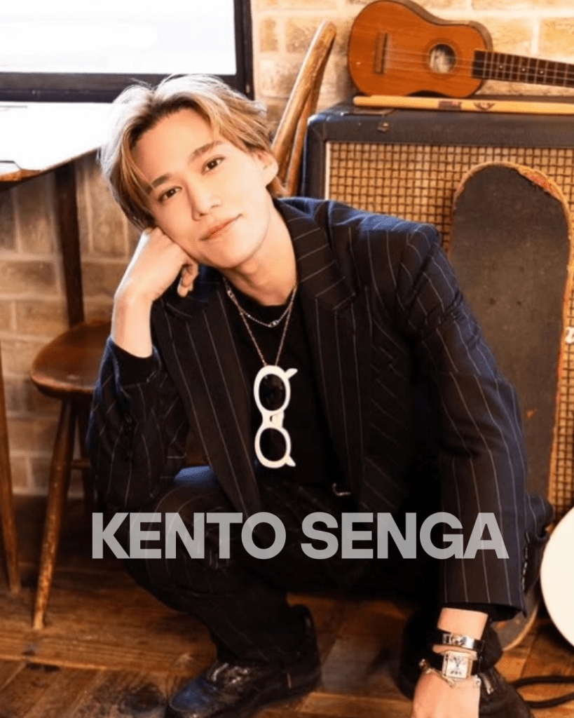 Kento Senga, a member of Kis-My-Ft2, posing in a stylish black striped suit, crouched near musical instruments with a playful expression.
