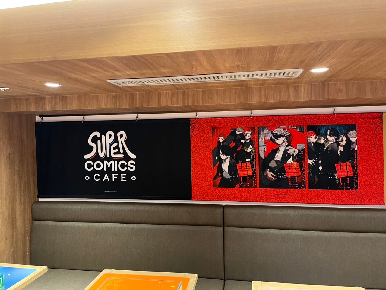 Interior view of the Super Comics Cafe featuring the cafe's logo and promotional artwork from SUPER EIGHT on a red background.