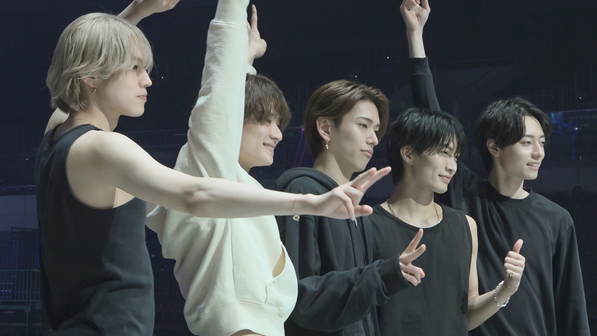 Five male idols posing together with raised arms and peace signs, showcasing their camaraderie and excitement for their upcoming performances.