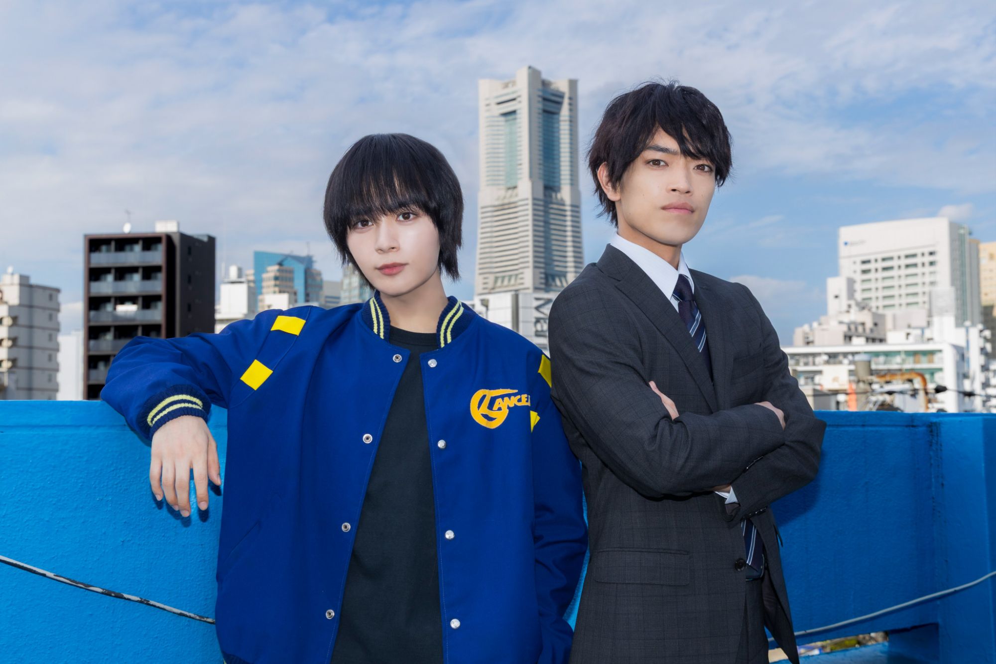 Ryusei Onishi and Yoshitaka Hara pose together in Yokohama with a city skyline in the background.
