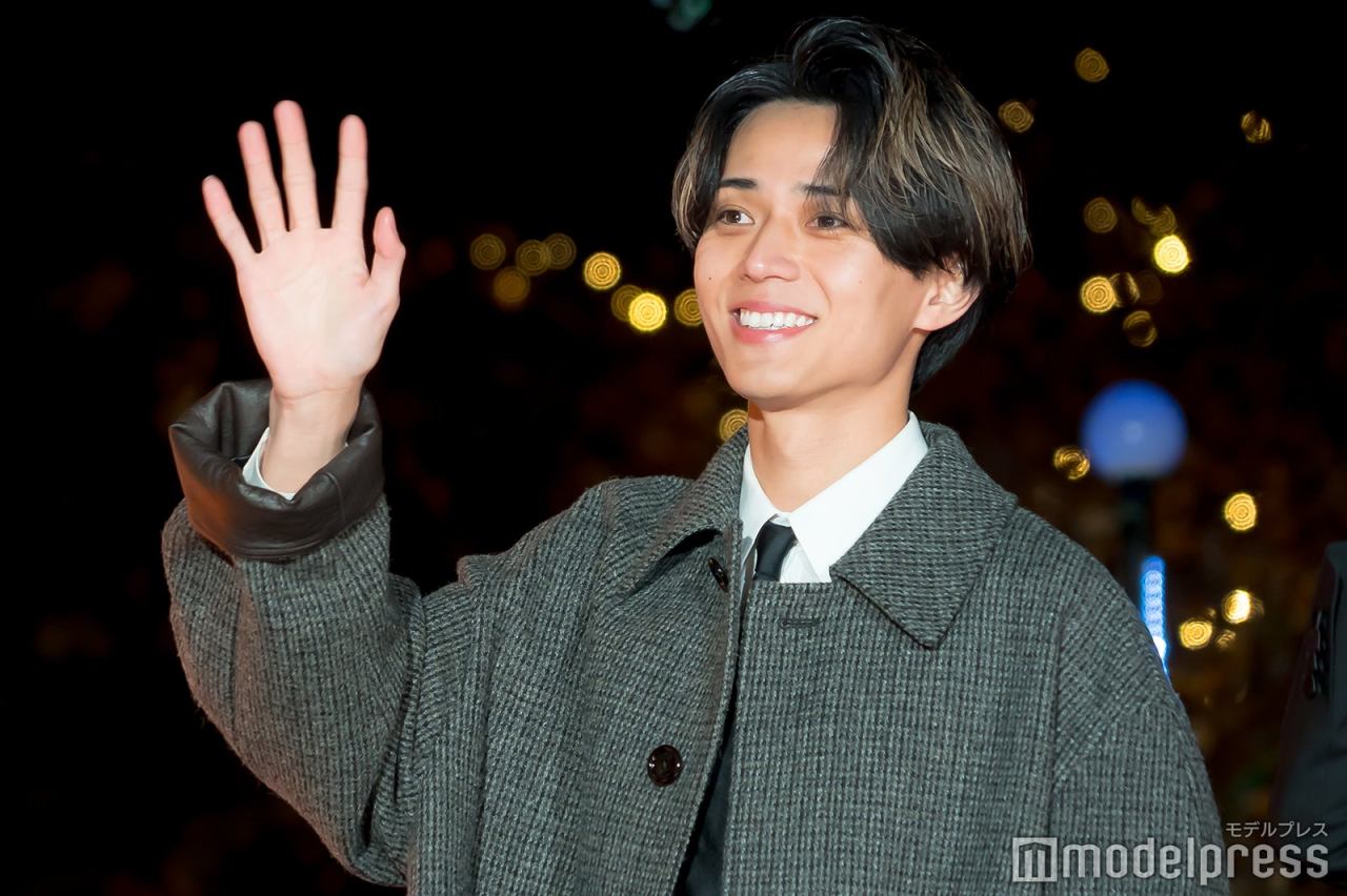 Ren Nagase waving at the camera during the premium lighting ceremony for the film '映画ラストマン -FIRST LOVE-' in Tokyo, surrounded by festive lights.