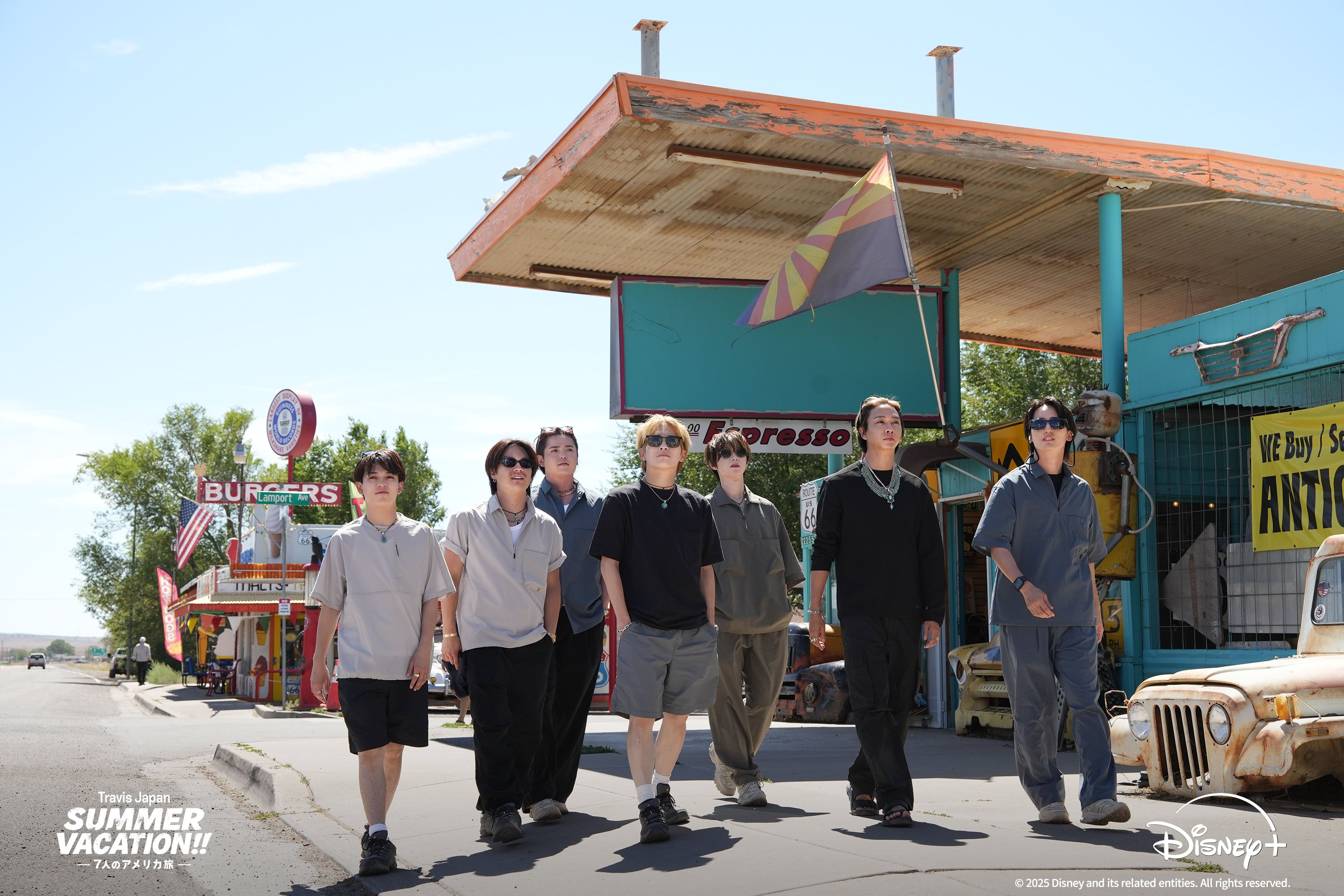 The members of Travis Japan walking together in a relaxed manner in front of a vintage roadside diner along Route 66, capturing a moment from their upcoming travel documentary.