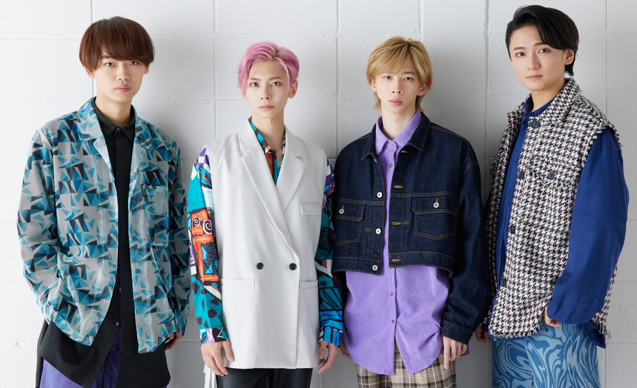 A group photo of the four members of the music group SpeciaL, standing together against a white wall, showcasing their diverse fashion styles.