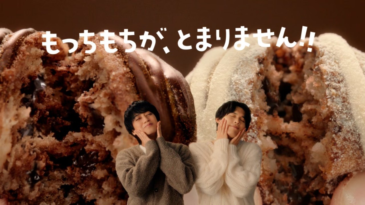 A close-up of two types of chocolate-filled donuts, with two male figures joyfully posing beside them, expressing delight. The background features a warm, chocolatey color scheme.