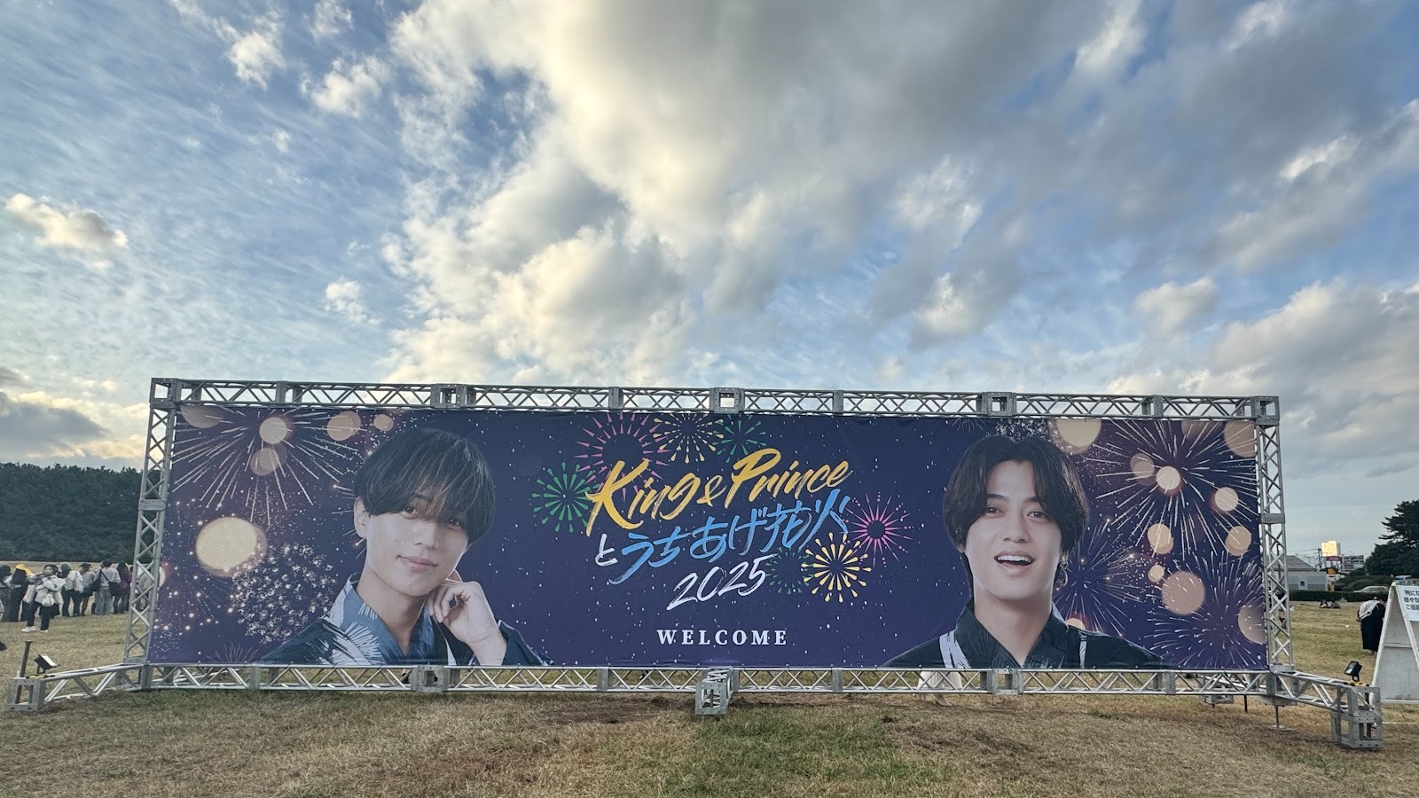 A welcome banner for the King & Prince fireworks event in 2025, featuring two members in festive outfits against a colorful background with fireworks imagery.