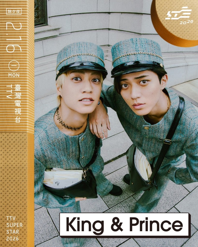 Two young male performers wearing matching outfits and hats, posing closely together outdoors with a backdrop of a building.