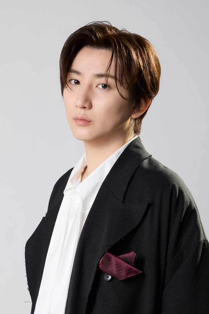 Portrait of Taiga Kyomoto, styled in a black blazer with a white shirt, showcasing a serious expression against a neutral background.