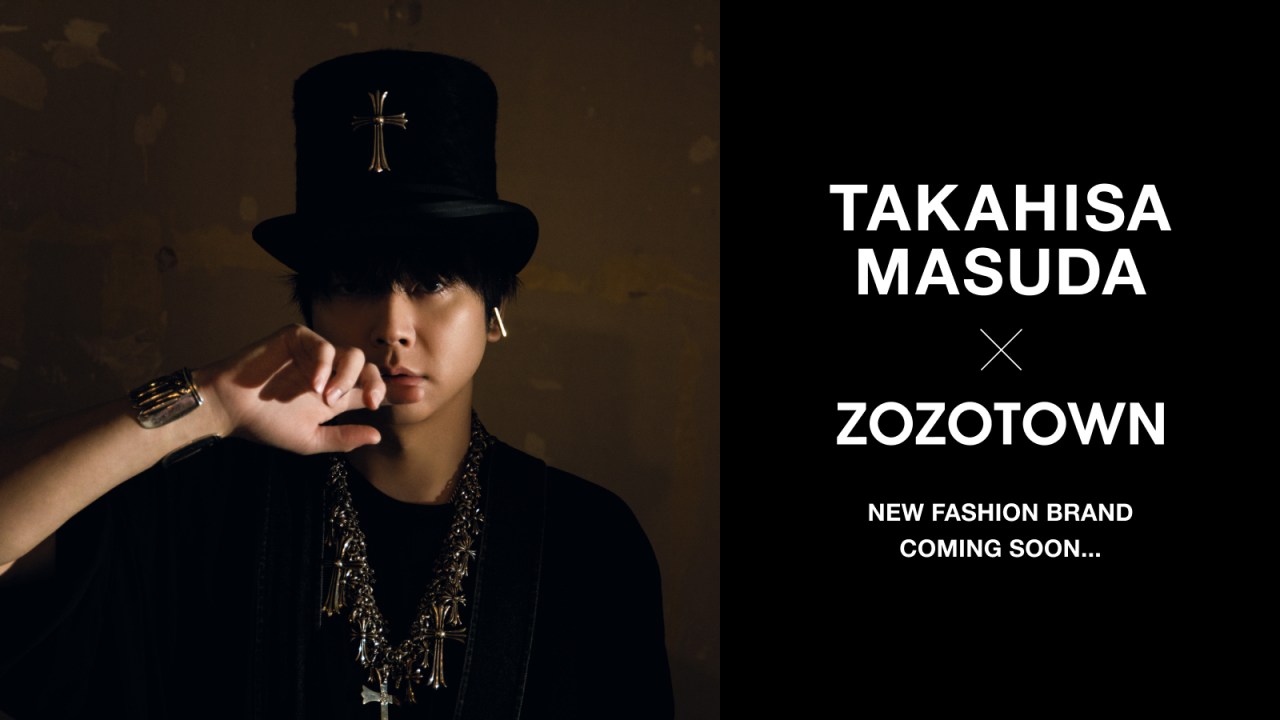 A fashion model wearing a black hat with a cross, adorned with jewelry, promoting a collaboration between Takahisa Masuda and ZOZOTOWN for a new fashion brand.