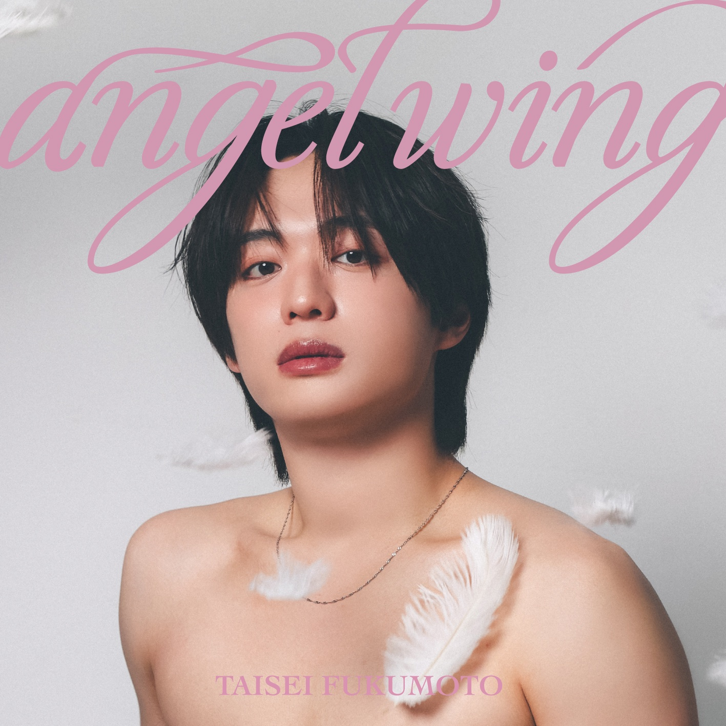 A portrait of a young person with long, dark hair, wearing a delicate necklace, looking directly at the camera with a subtle expression. Soft white feathers float around them, with the text 'angeltwing' in pink font above and 'TAISEI FUKUMOTO' below.