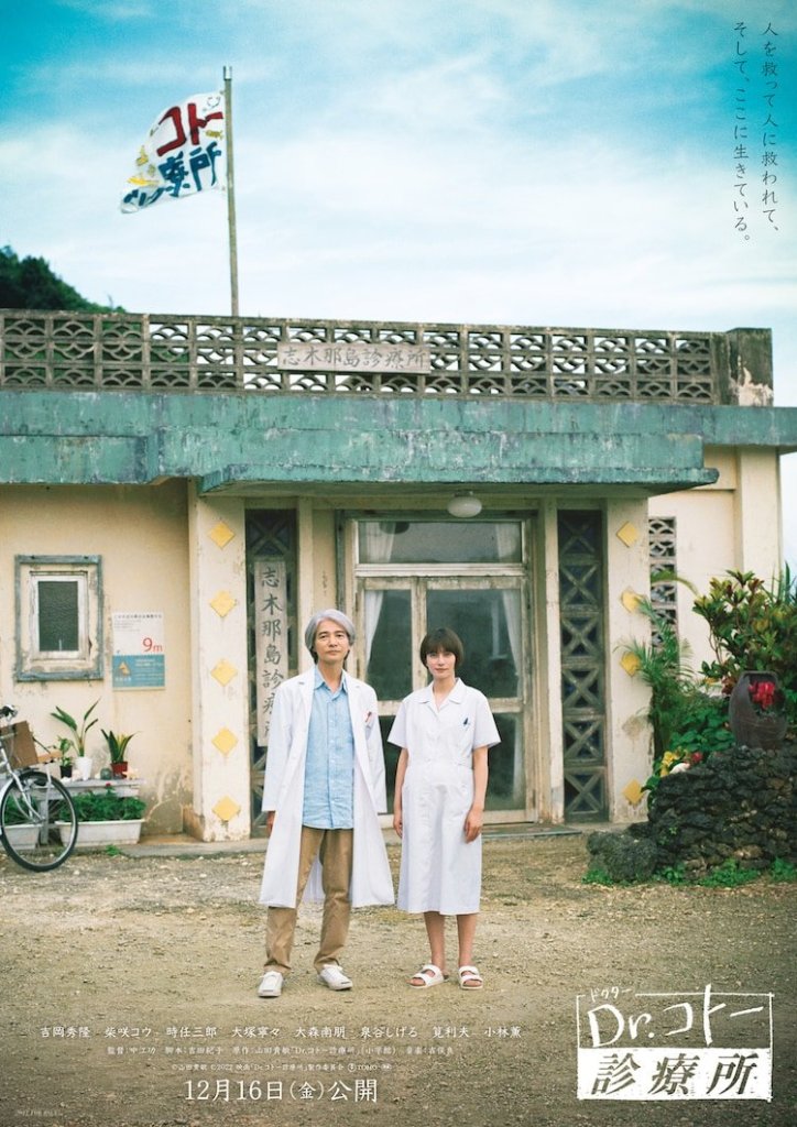 A doctor and nurse stand together in front of a medical clinic building, with a flag waving in the background and a bicycle nearby. The scene captures a serene atmosphere with a blue sky overhead.